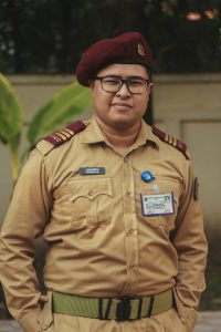 Man in uniform with ID card posing outdoors in Dhaka, Bangladesh.